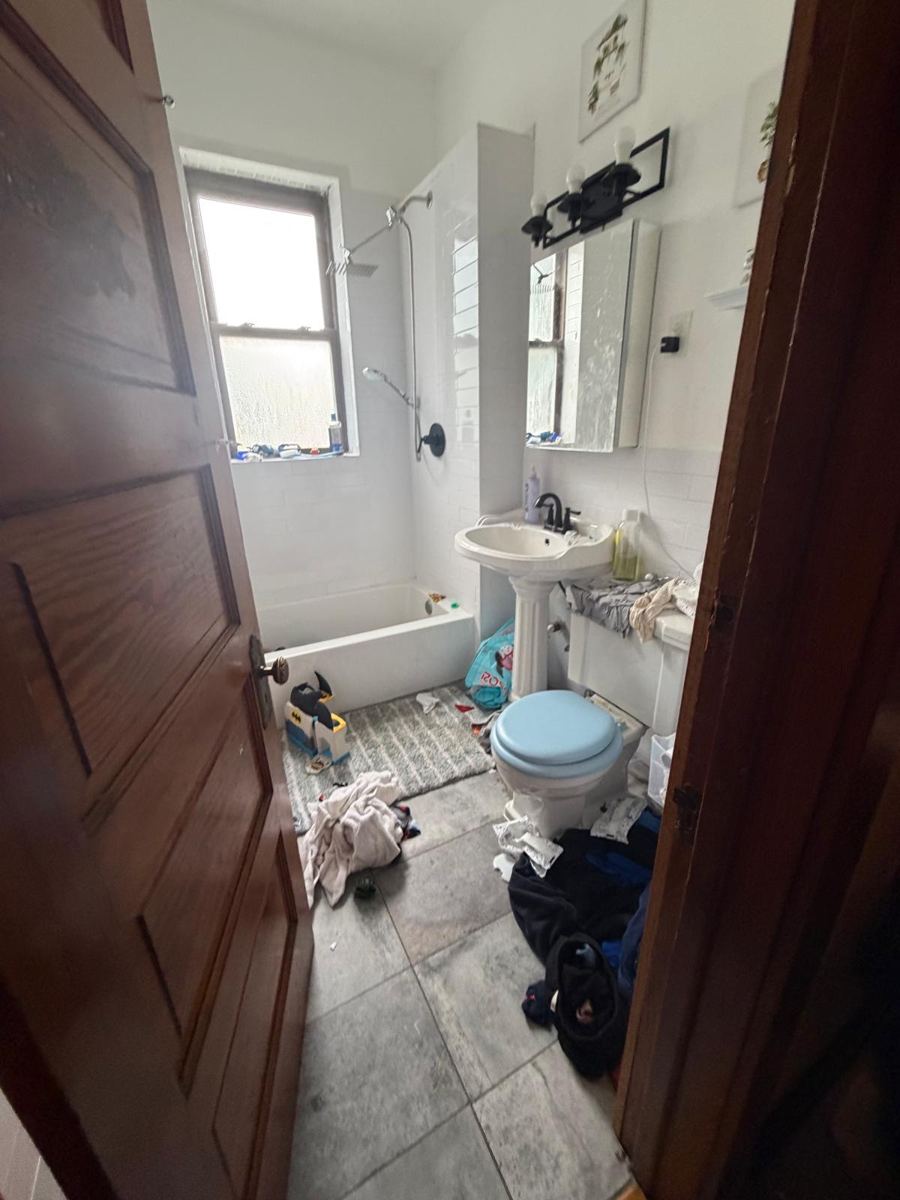 Bathroom with clothes and clutter on the floor