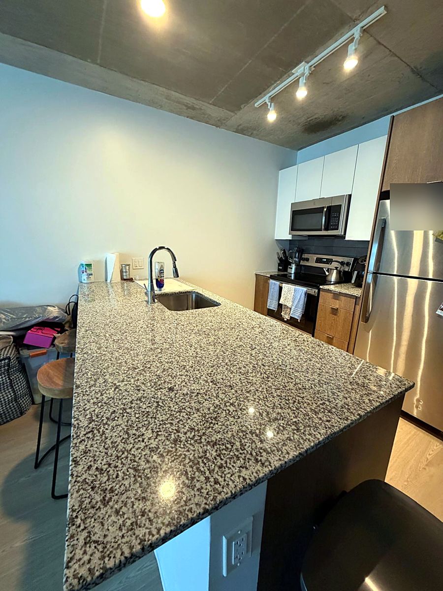 Granite kitchen island and counters wiped down, stainless appliances polished