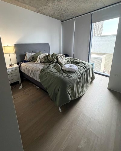 The same bedroom before: unmade bed and cords across the floor