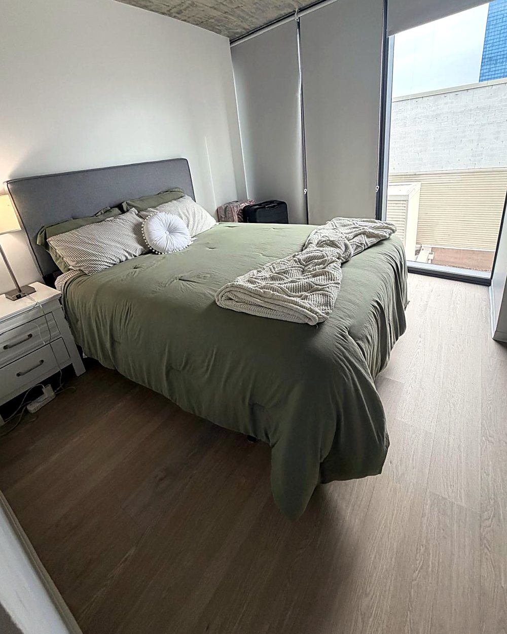 Bright Chicago apartment bedroom after a Fairy Cleaning visit: bed made, floors clear, floor-to-ceiling windows