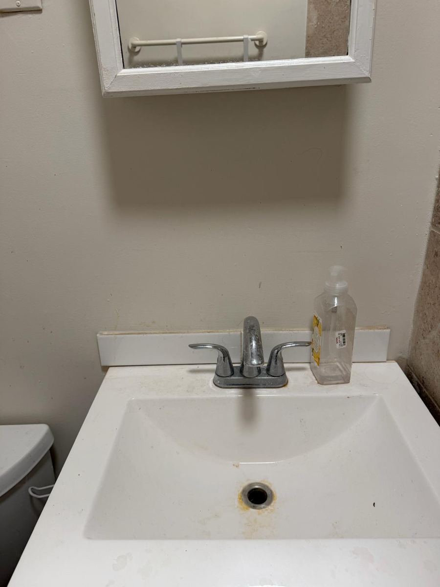 Bathroom sink with a stained drain and dull faucet