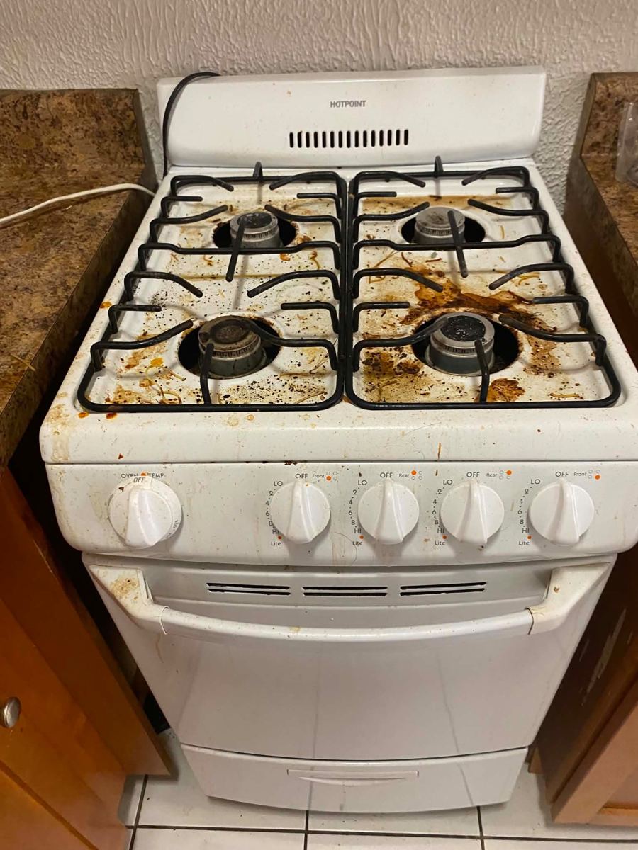 White gas stovetop covered in grease and food spills